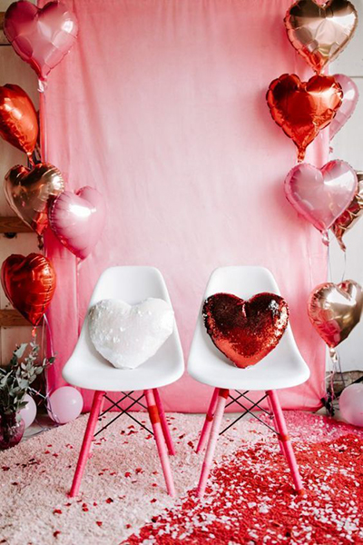 deux chaises blanches devant un rideau avec des ballons en forme de coeur