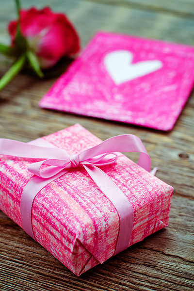 une rose rouge et cadeau avec une carte sur une table